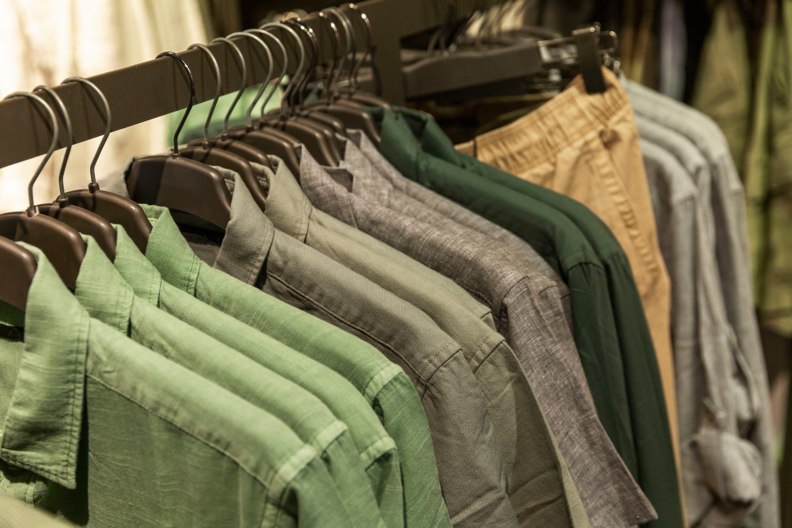 Men’s summer shirts in different colors on hangers in the store. Style, fashion and comfort. Close-up.
