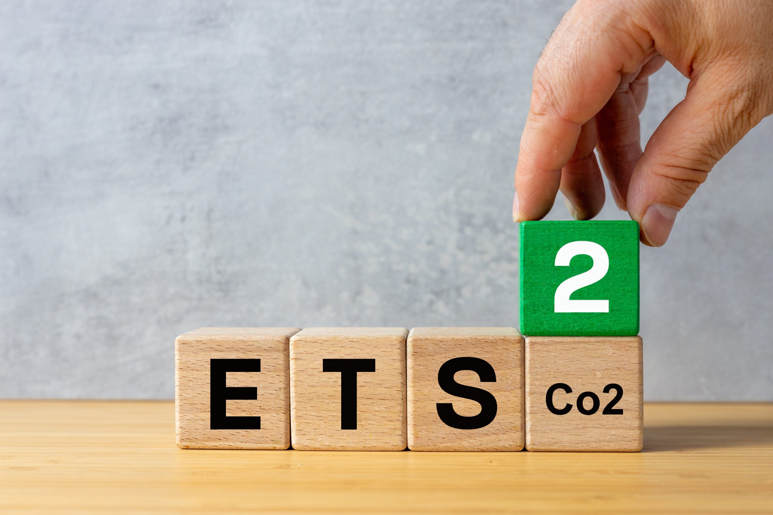 ETS 2 European Trading System. Business, environmental concept. Text ETS on wooden blocks and a businessman’s hand adding a cube with the number two. New System for Trading in Carbon Emission Permits.